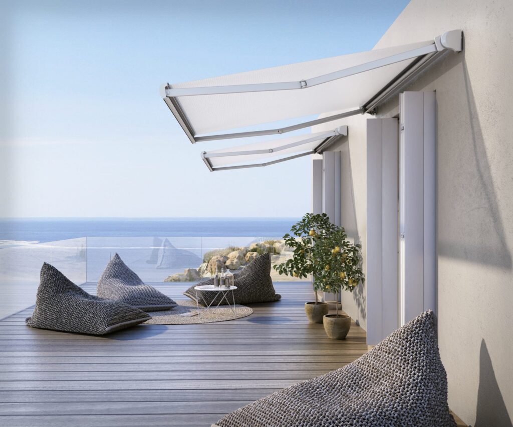 Coastal home with sea views and two Base Lite awnings covering a patio with textured grey bean bags