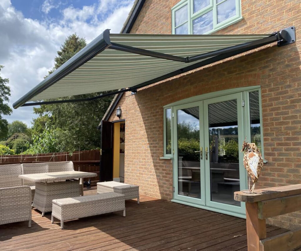 Retractable awning with green striped fabric on a UK home