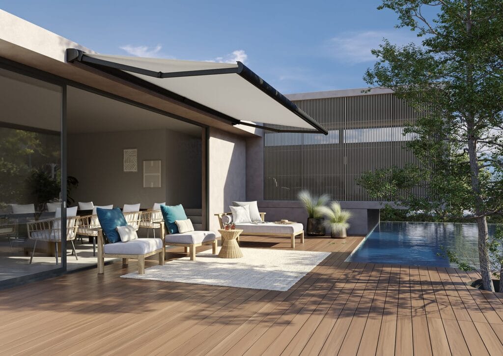 Base Plus awning providing shade for three pieces of garden furniture on decking next to a pool