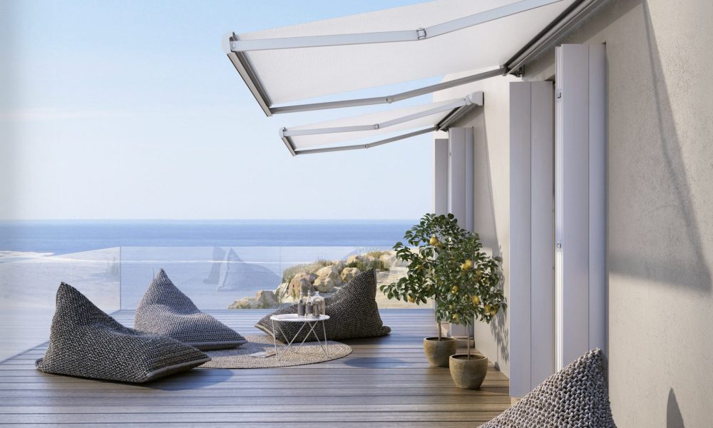 Coastal home with sea views and two Base Lite awnings covering a patio with textured grey bean bags