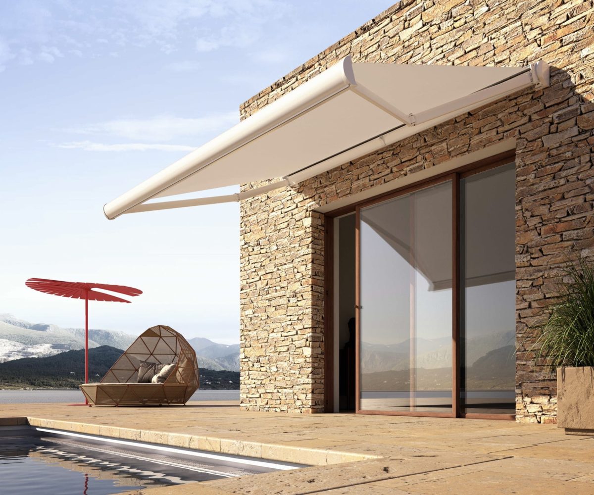 Home on a lakeside with steps leading down to the water and white retractable awning by Base Direct shading the doors