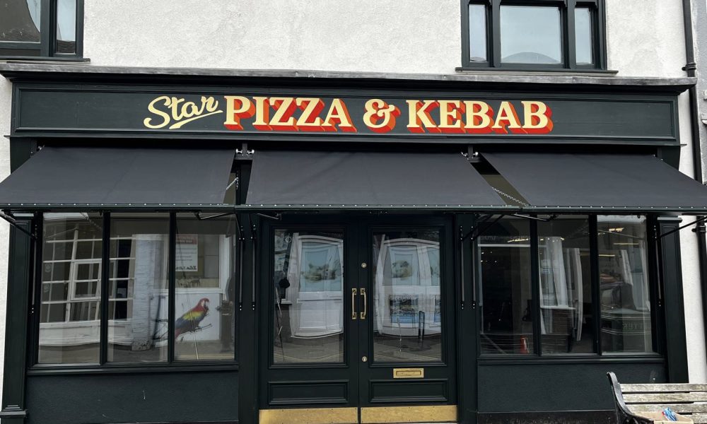 A shopfront painted with black accents and branding across the top that reads "Star Pizza & Kebab". Three black Victorian awnings are installed on the shopfront over the windows and beneath the signage.