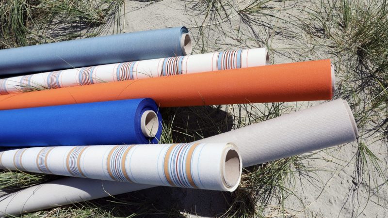 Rolls of fabric in various colours and patterns including white, blue, orange and stripes