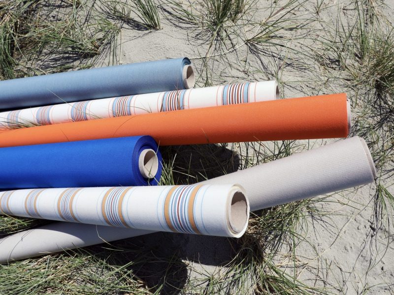 Rolls of fabric in various colours and patterns including white, blue, orange and stripes