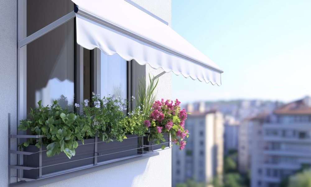 Many plants lining a windowsill, shaded by a white Italia Slim drop arm awning
